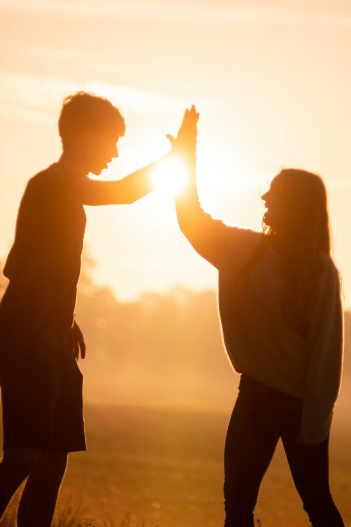 Zwei Menschen die sich vor einem Sonnenuntergang einen "High-Five" geben