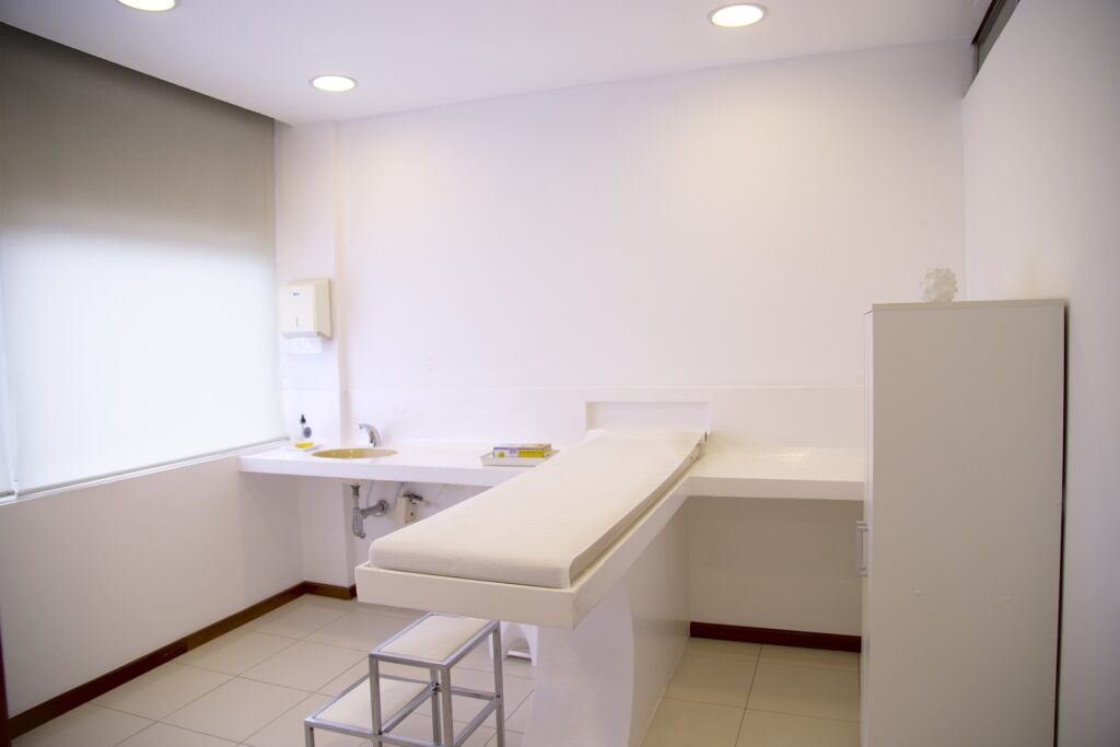 Das Bild zeigt ein typisches Behandlungszimmer beim Arzt mit einer Liege in der Mitte des Raumes